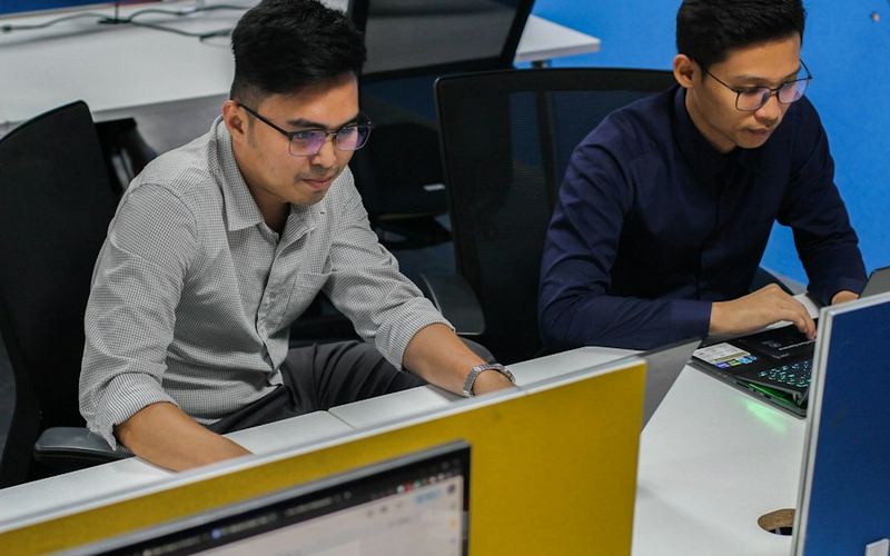 Dois colegas trabalhando juntos em computadores no escritório